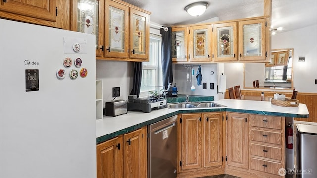 kitchen with freestanding refrigerator, dishwasher, a sink, a peninsula, and glass insert cabinets