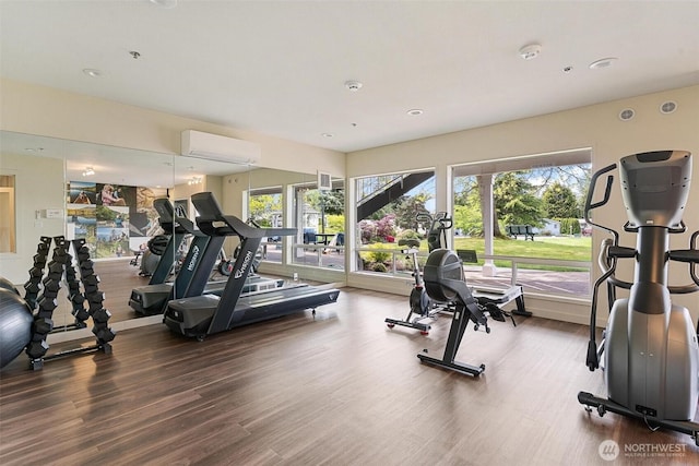 gym with wood finished floors, a wall unit AC, and recessed lighting