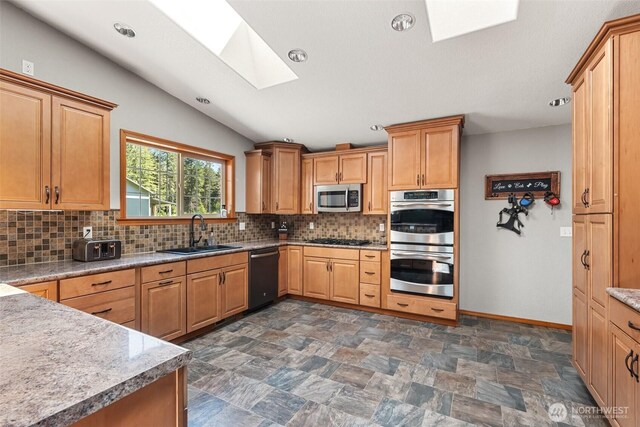 12430 Brooks St SW, Olympia, WA 98512 - kitchen featuring vaulted ceiling with skylight, appliances with stainless steel finishes, tasteful backsplash, a sink, and recessed lighting