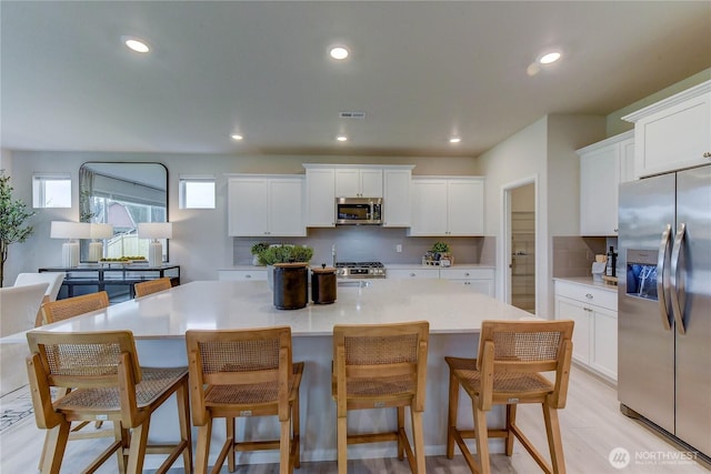 kitchen with light countertops, appliances with stainless steel finishes, a kitchen island, and white cabinets