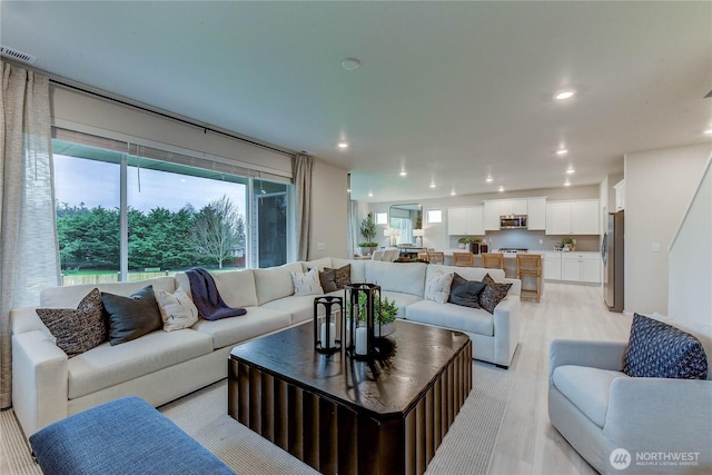 living area with recessed lighting, visible vents, and light wood-type flooring
