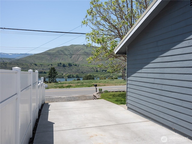 view of patio / terrace with fence and a water and mountain view