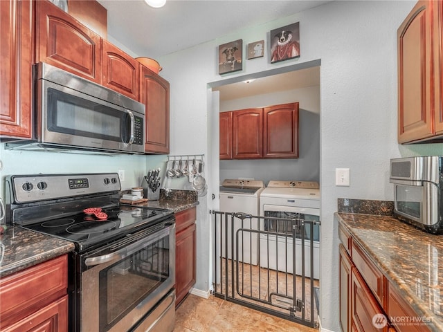 kitchen with washing machine and clothes dryer, stainless steel appliances, and dark stone counters
