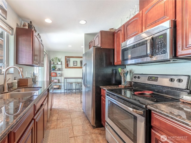 kitchen featuring a sink, dark stone counters, stainless steel appliances, recessed lighting, and light tile patterned floors
