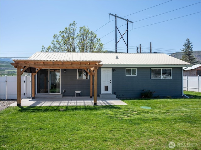 rear view of house featuring a lawn, a patio area, fence, and metal roof