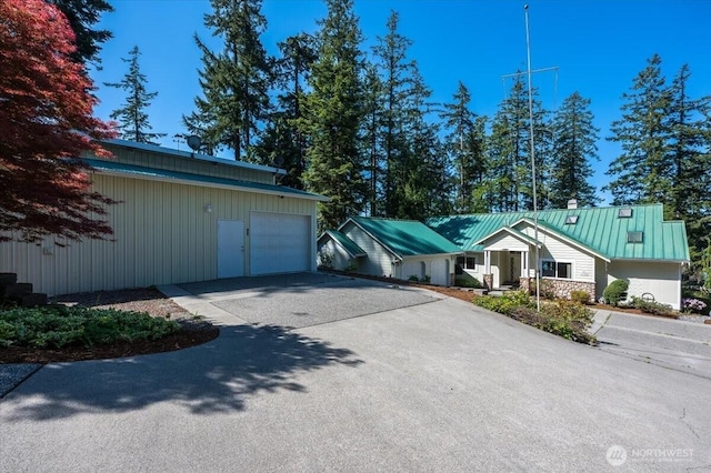 view of front of property featuring an outbuilding, driveway, and metal roof