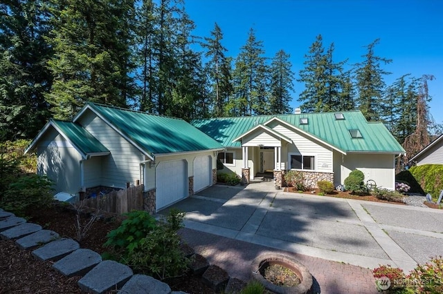 single story home with a standing seam roof, metal roof, stone siding, and a garage