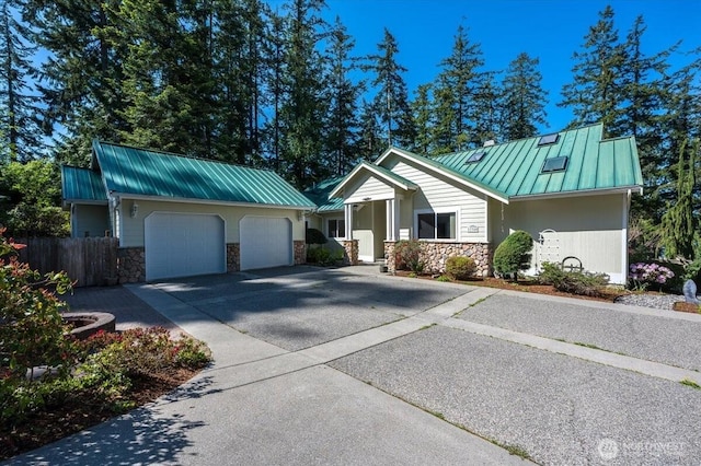 view of front of house with an attached garage, metal roof, stone siding, and a standing seam roof