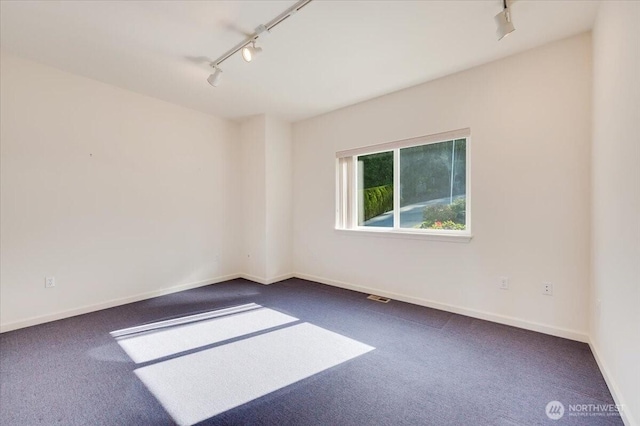 unfurnished room featuring carpet floors, rail lighting, baseboards, and visible vents