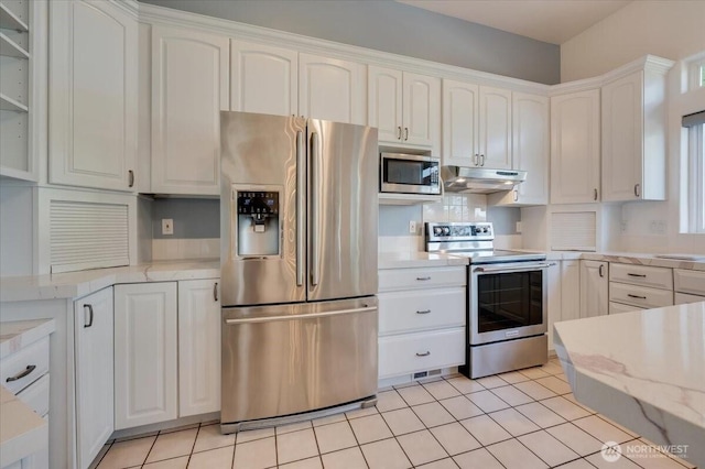 kitchen featuring light tile patterned flooring, white cabinetry, under cabinet range hood, light stone counters, and appliances with stainless steel finishes