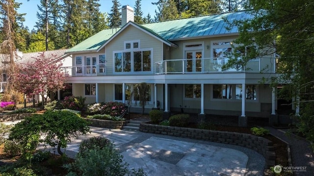 rear view of property with a patio, a chimney, and metal roof