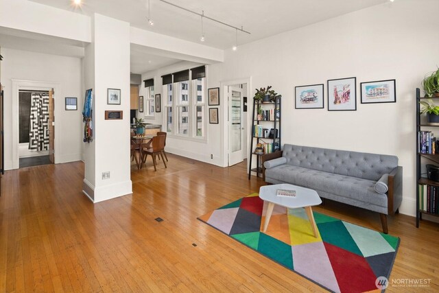 living room with rail lighting, wood finished floors, and baseboards