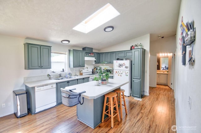 117 Hewitt Rd, Chehalis, WA 98532 - kitchen with white appliances, a breakfast bar area, light countertops, a sink, and light wood finished floors