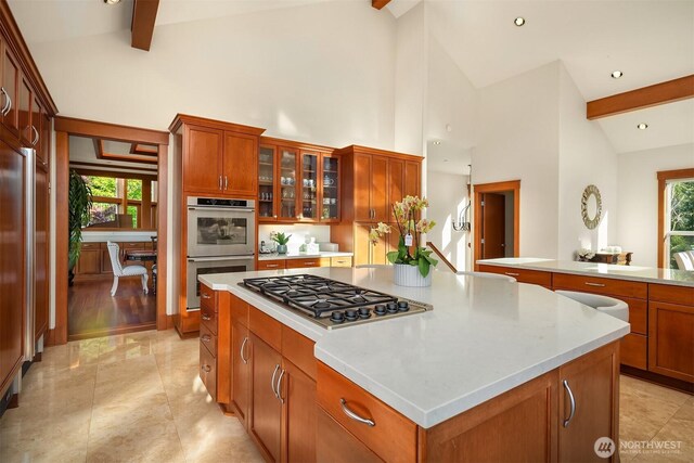 15803 Uplands Way SE, North Bend, WA 98045 - kitchen featuring appliances with stainless steel finishes, a center island, beam ceiling, light countertops, and glass insert cabinets