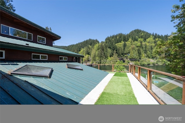 exterior space featuring metal roof, a wooded view, and a water view