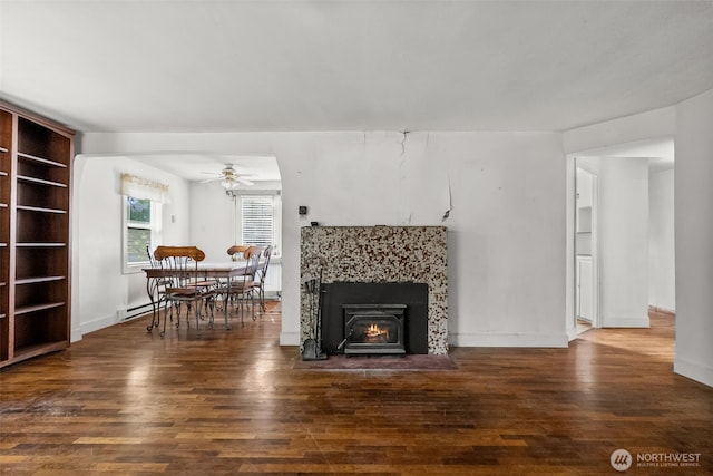 living room with a baseboard radiator, wood finished floors, ceiling fan, and a lit fireplace