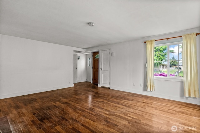empty room with wood finished floors, baseboards, and a smoke detector