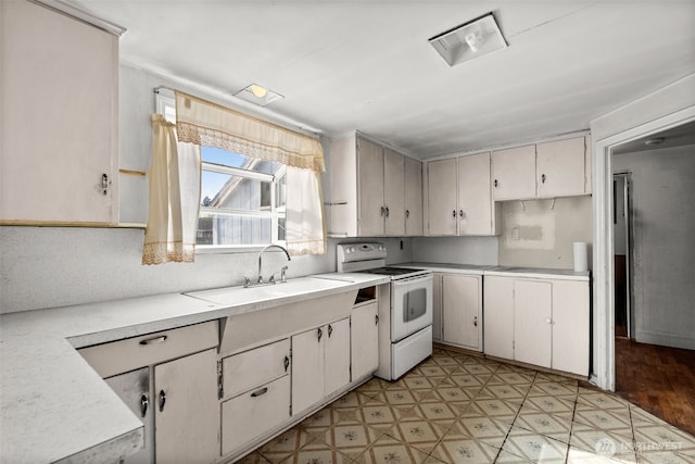 kitchen featuring electric stove, a sink, light countertops, and white cabinetry