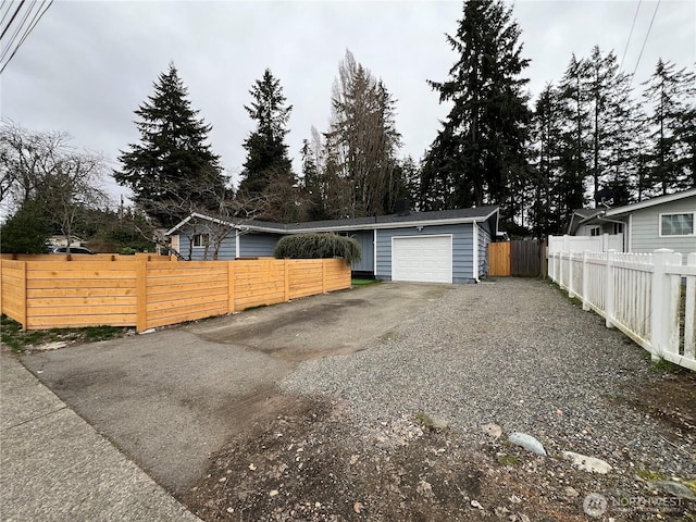 exterior space featuring fence private yard, a garage, and aphalt driveway