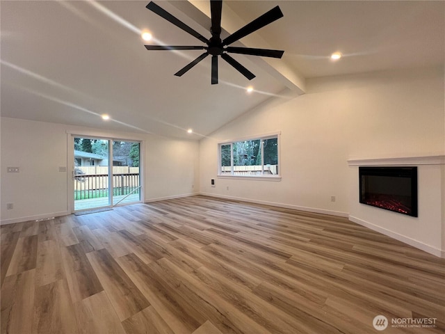 unfurnished living room with ceiling fan, a glass covered fireplace, baseboards, vaulted ceiling with beams, and wood finished floors