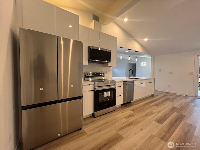 kitchen featuring appliances with stainless steel finishes, a sink, visible vents, light countertops, and vaulted ceiling