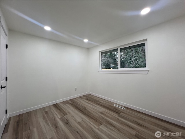 empty room with baseboards, recessed lighting, wood finished floors, and visible vents