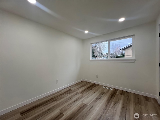 empty room with baseboards, recessed lighting, wood finished floors, and visible vents