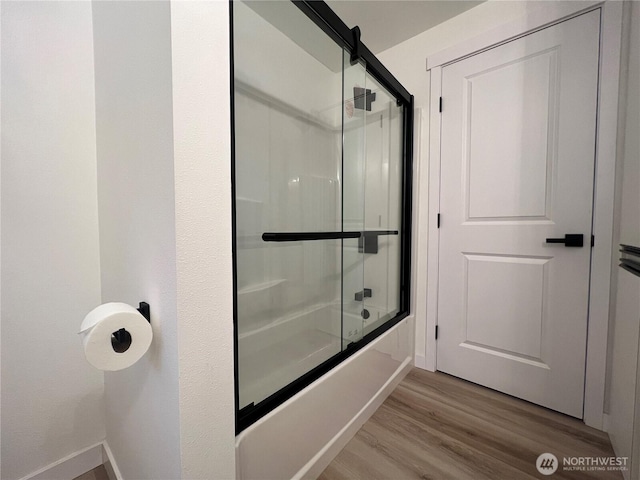 bathroom with baseboards, enclosed tub / shower combo, and wood finished floors