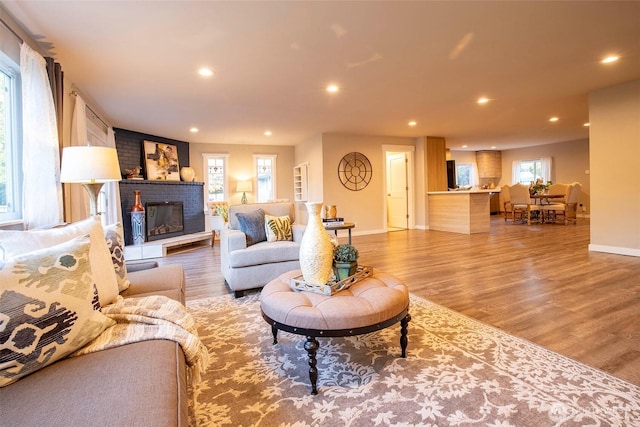 living room featuring a fireplace, recessed lighting, baseboards, and light wood-style floors