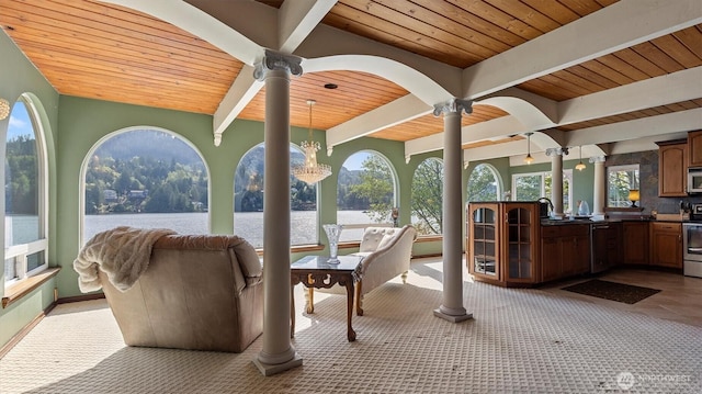 sunroom / solarium featuring a water view, beamed ceiling, and a sink