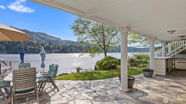 view of patio with stairs, outdoor dining area, area for grilling, and a water and mountain view