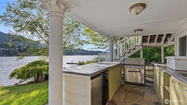 view of patio with area for grilling, exterior kitchen, a sink, a water view, and stairs