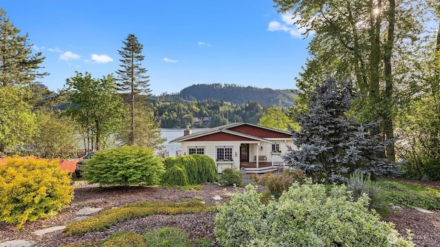 rear view of property with a porch, a mountain view, and a chimney