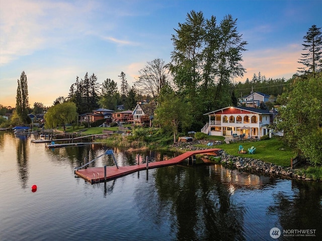 view of dock with a yard and a water view