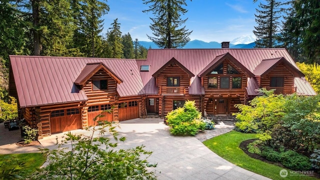 log home featuring concrete driveway, log exterior, a chimney, and metal roof