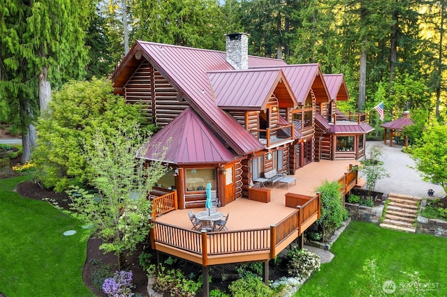 rear view of property featuring a deck, a chimney, a standing seam roof, log exterior, and metal roof
