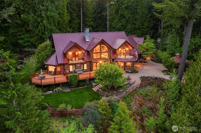 back of property with a deck, a chimney, a forest view, a standing seam roof, and metal roof