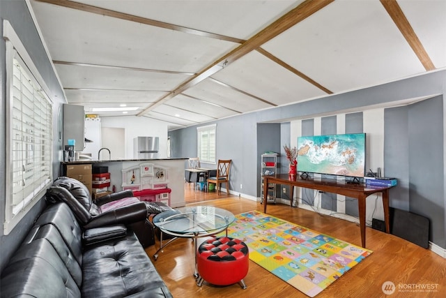 living area featuring baseboards, vaulted ceiling, and wood finished floors