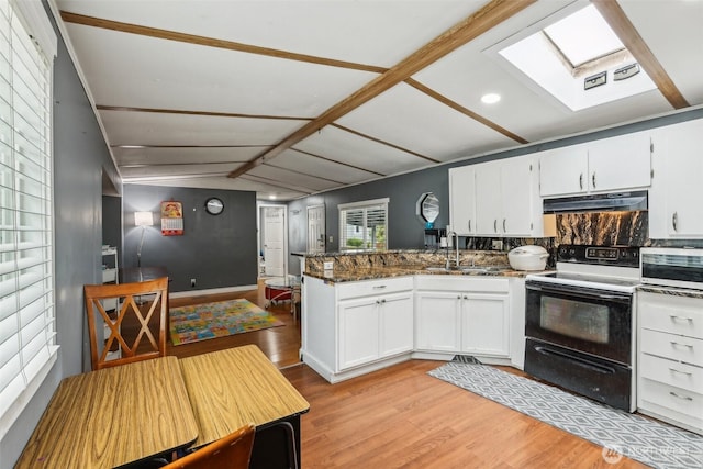 kitchen featuring a peninsula, under cabinet range hood, a sink, light wood finished floors, and range with electric cooktop