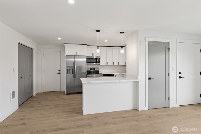 kitchen with appliances with stainless steel finishes, light countertops, recessed lighting, white cabinetry, and a peninsula