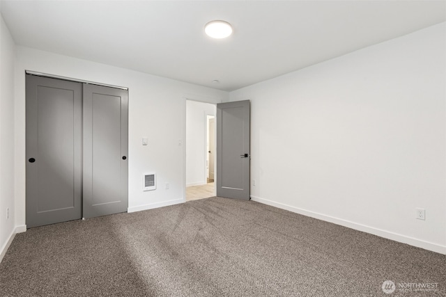 unfurnished bedroom with carpet floors, baseboards, visible vents, and a closet