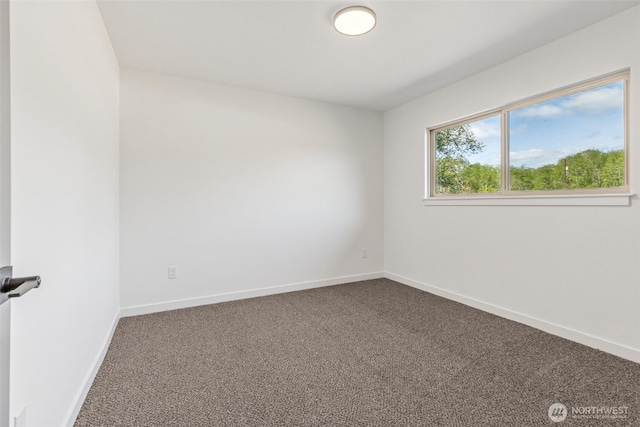 empty room with baseboards and dark carpet