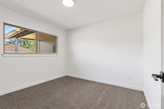empty room with baseboards and dark colored carpet