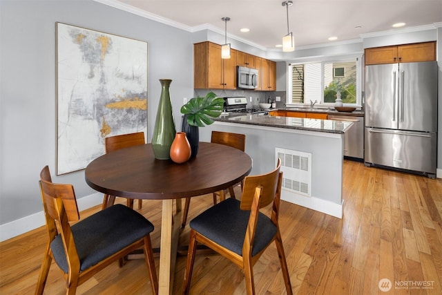 kitchen with a sink, appliances with stainless steel finishes, crown molding, and visible vents