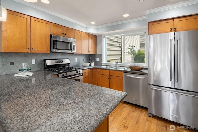 kitchen featuring brown cabinets, light wood-style floors, stainless steel appliances, and a sink