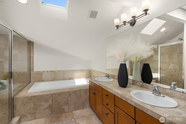 full bathroom featuring a bath, visible vents, vaulted ceiling with skylight, and a sink