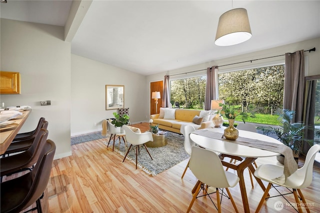 living room with baseboards, light wood finished floors, and vaulted ceiling