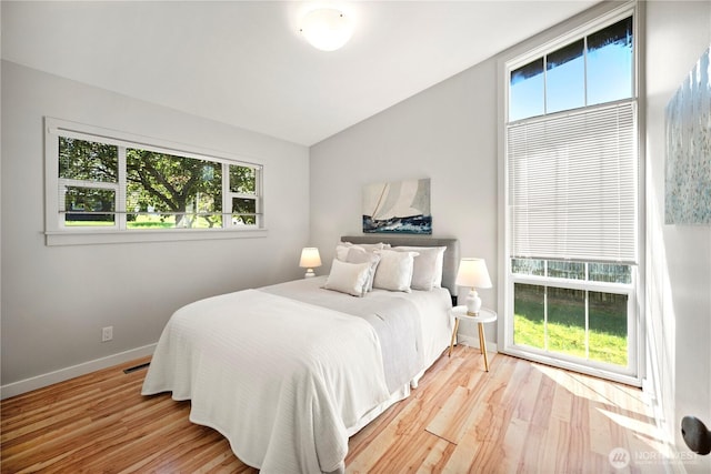 bedroom with baseboards, light wood-style flooring, and multiple windows