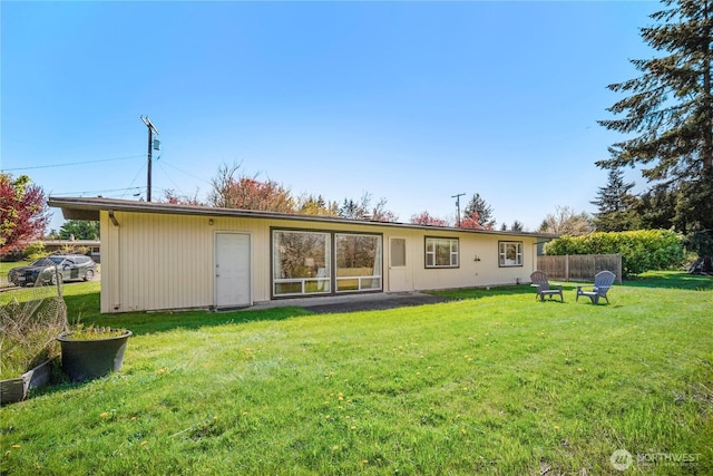 back of house featuring a lawn and fence
