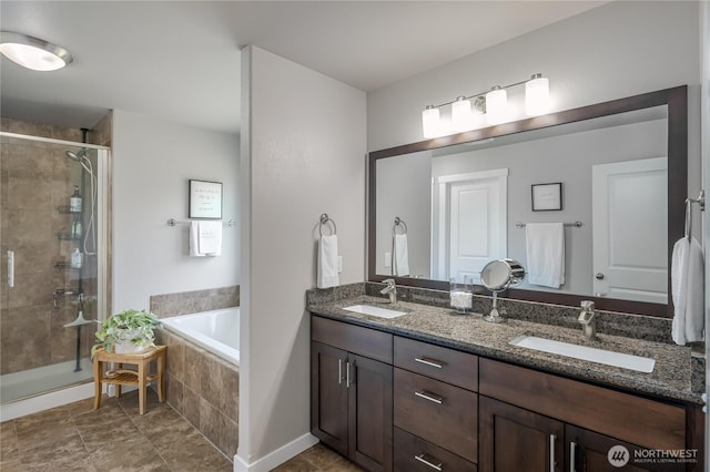 full bath with a sink, double vanity, a shower stall, and a garden tub